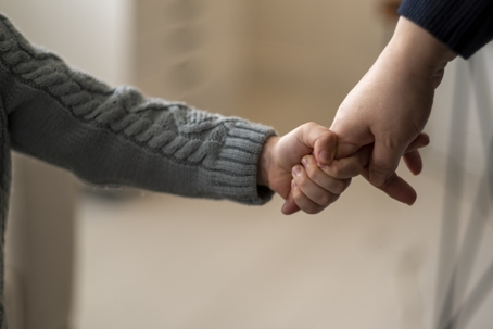 small child holding onto parent's hand