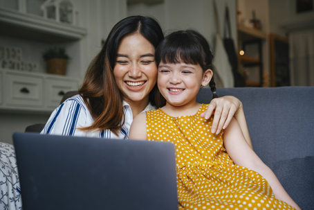 happy mother and daughter looking at a laptop